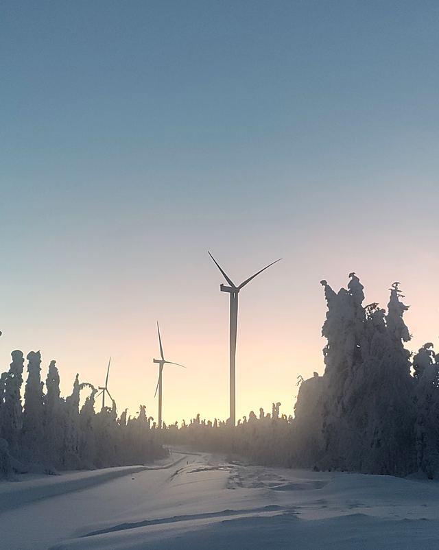 Tuulivoimaloita talvisessa pohjoisen maisemassa auringonnousun aikaan